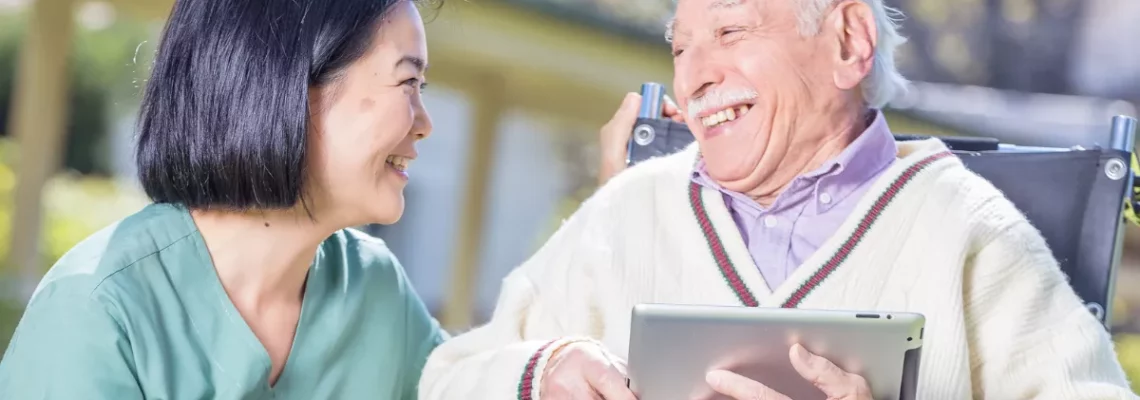 senior man in wheelchair smiling with caregiver