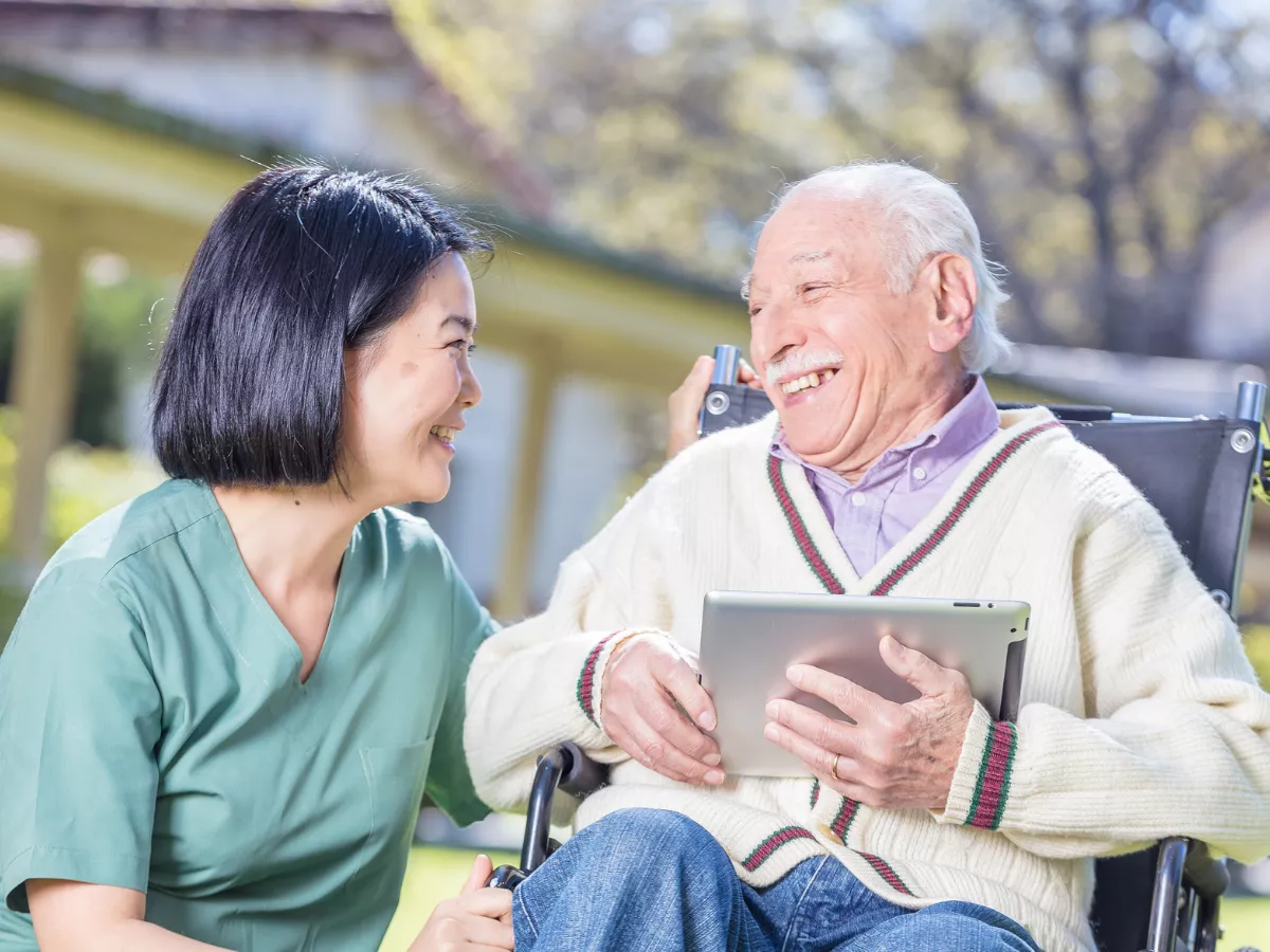 senior man in wheelchair smiling with caregiver