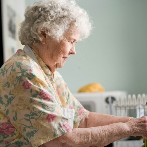 elderly woman using sink in kitchen