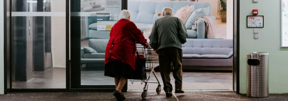 An Elderly couple with a shopping cart entering a retail store underscoring the need for a checklist for aging parents.